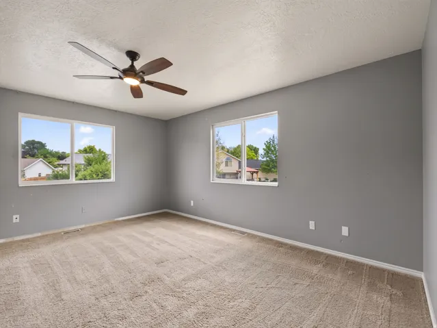 Carpeted room with a ceiling fan featuring integrated lighting