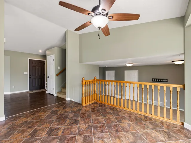 Entryway featuring a dark wood-finish door, wood-finish flooring, and a staircase