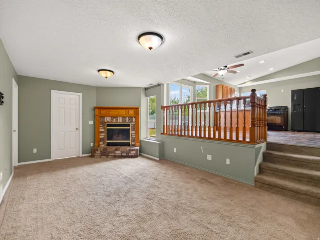 Carpeted room featuring a brick fireplace with a wood mantle