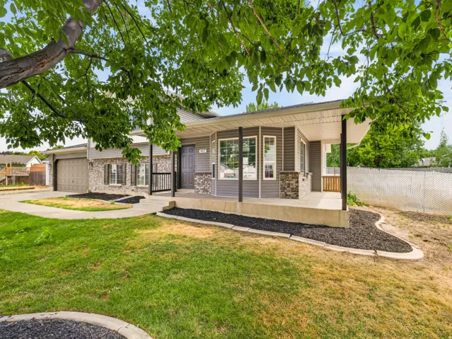 Ranch-style residence featuring a covered porch, an attached garage, bay windows, and stone veneer accents