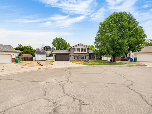 Split-level residence featuring a two-car garage with a dark wood-finish door, stone façade accents, and a covered front porch