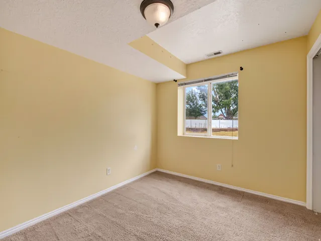 Interior room featuring neutral-toned carpeting, light yellow painted walls, and white baseboards
