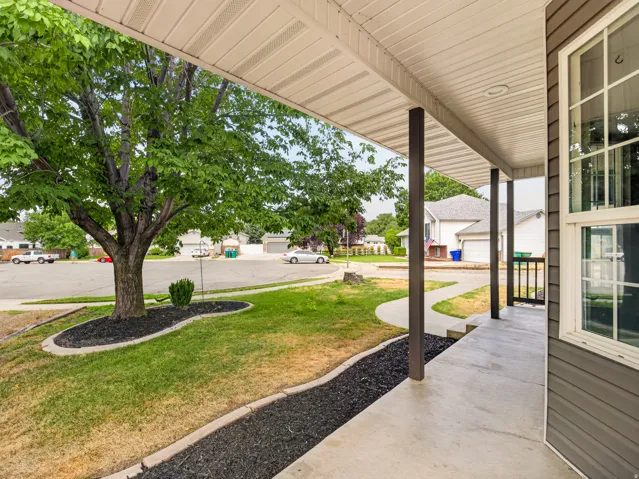 Inviting front porch featuring a white vinyl soffit ceiling, dark support columns, and grey horizontal siding
