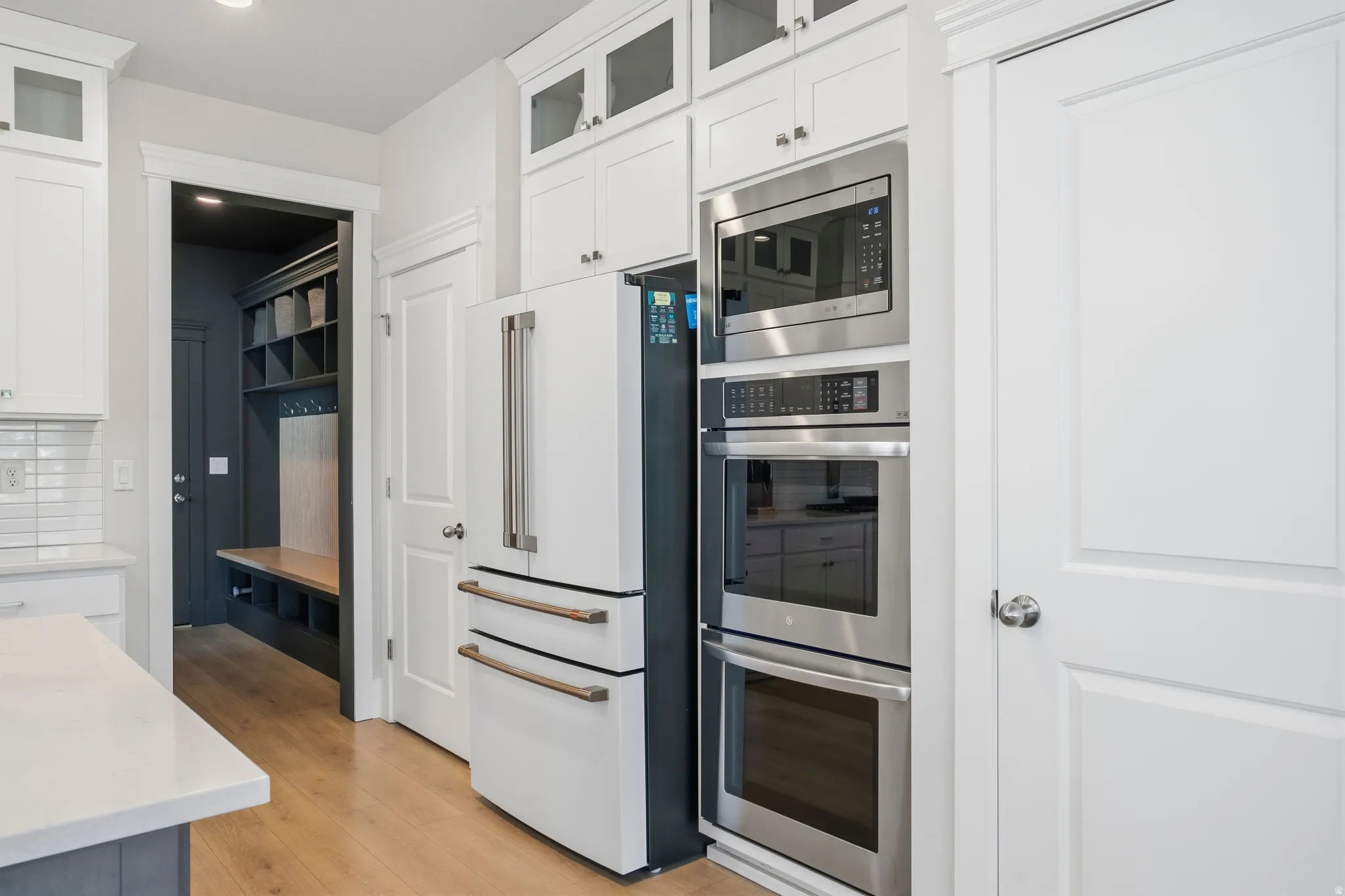 Kitchen featuring white cabinetry, built-in stainless steel appliances including a microwave and double oven, and wood-finish flooring