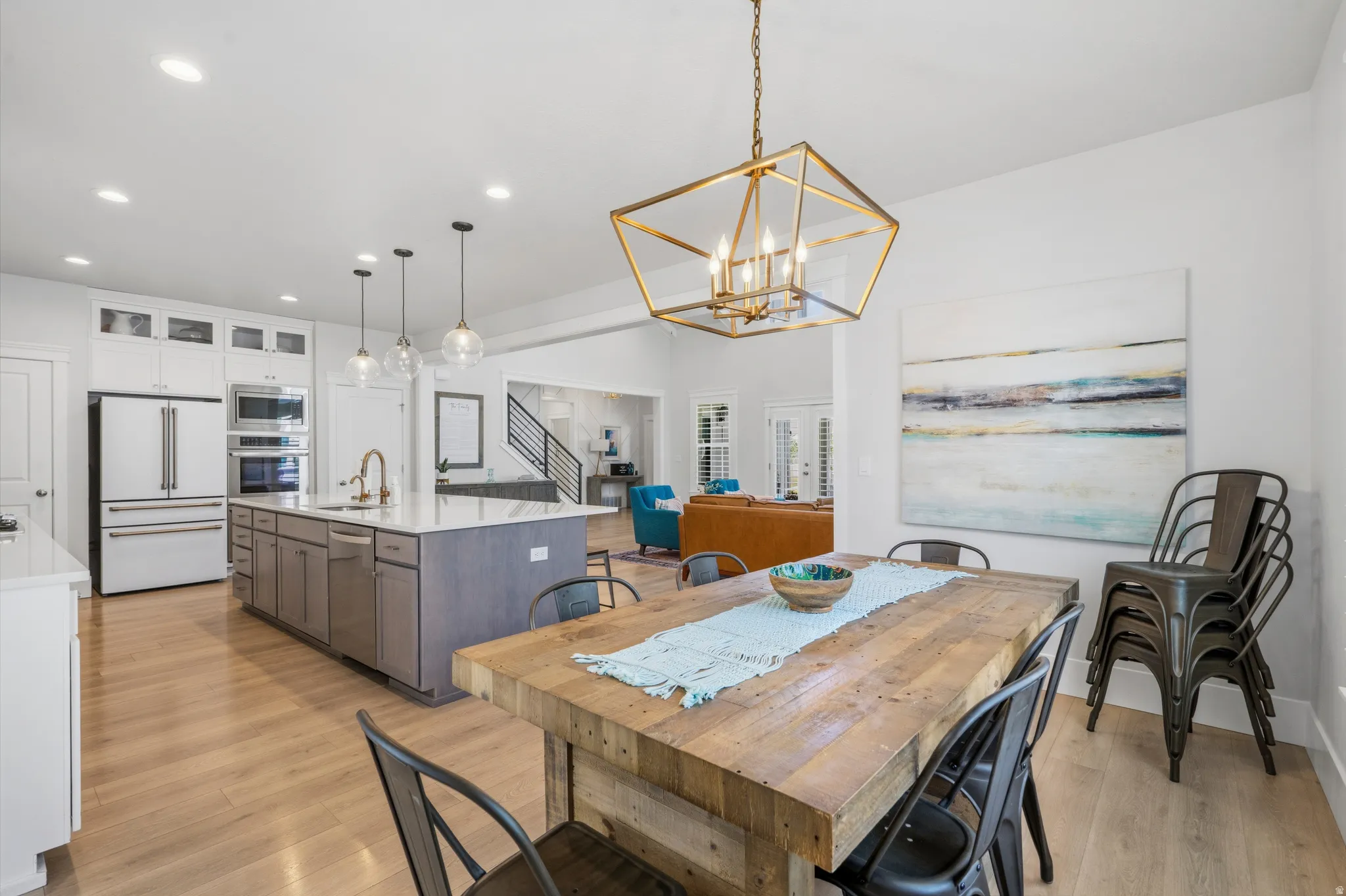 Open-concept dining area with wood-finish flooring, a contemporary brass chandelier, and recessed lighting