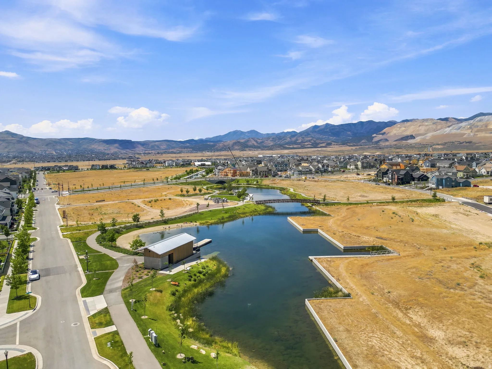 Community lake with a boat house, a pedestrian bridge, and surrounding green spaces