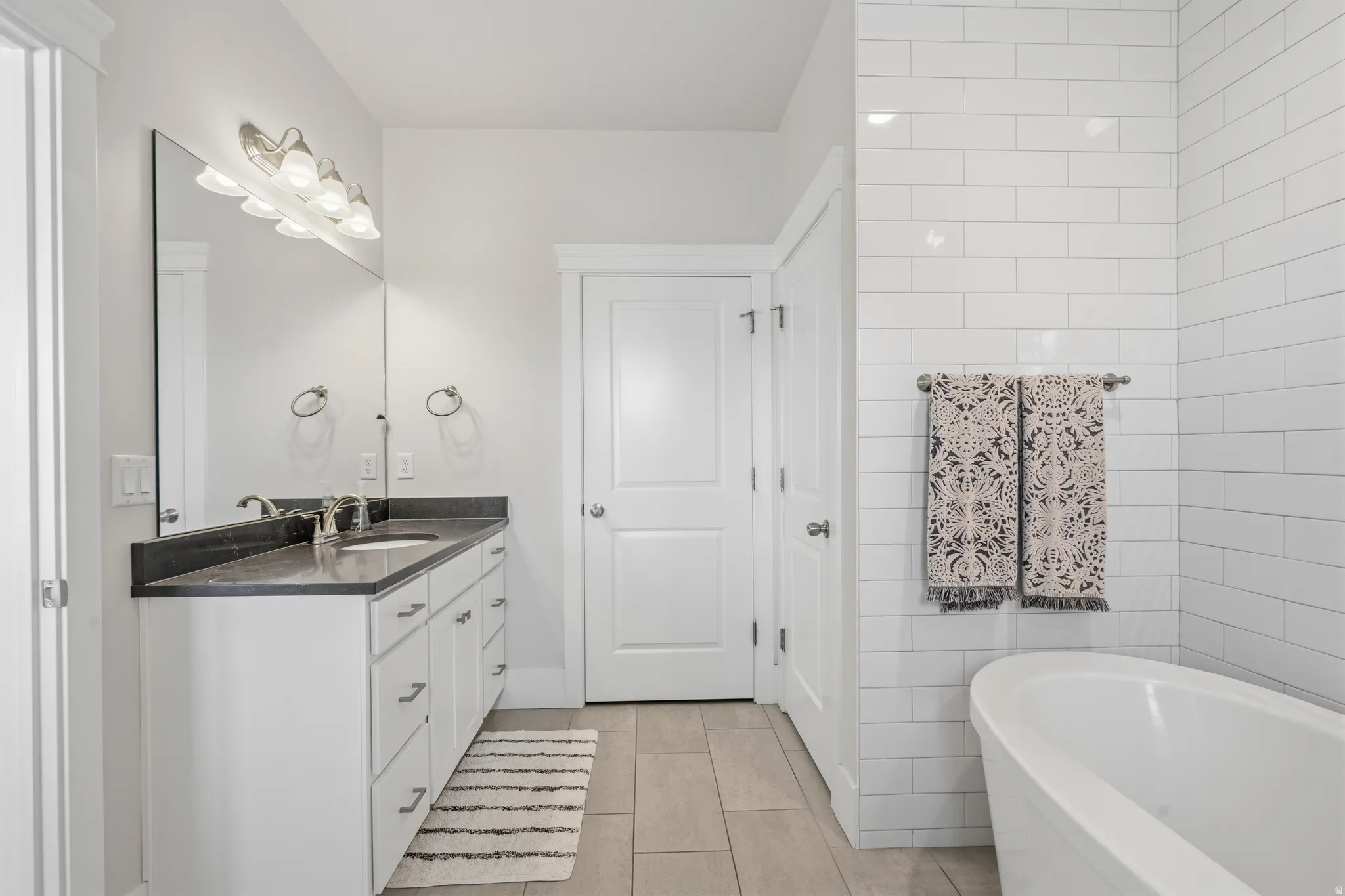 Bathroom with a freestanding soaking tub and white subway tile surround