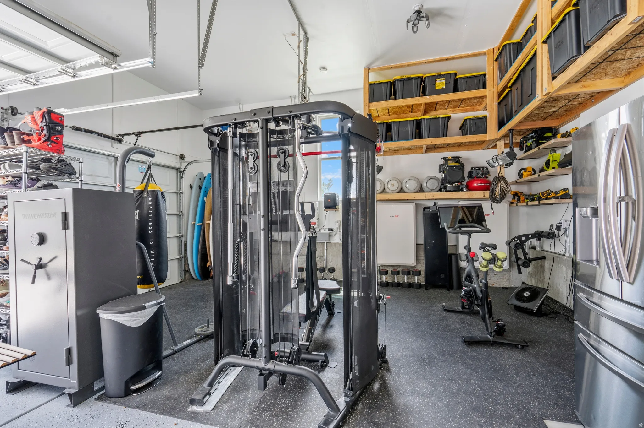 Garage space featuring durable rubber flooring, extensive overhead wood shelving, wall-mounted utility shelving, and recessed lighting