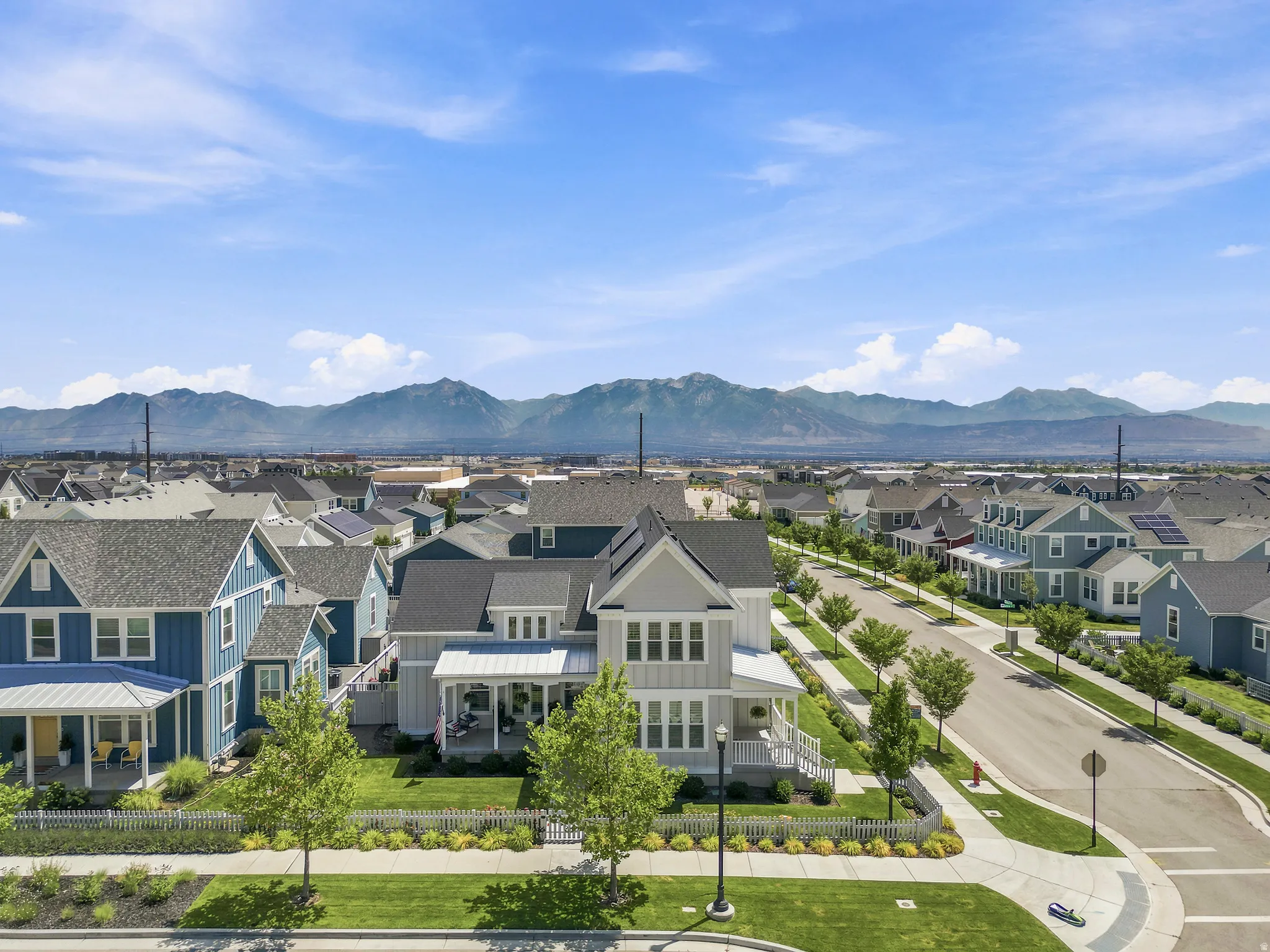 Modern residential neighborhood featuring a tree-lined street and mountain backdrop