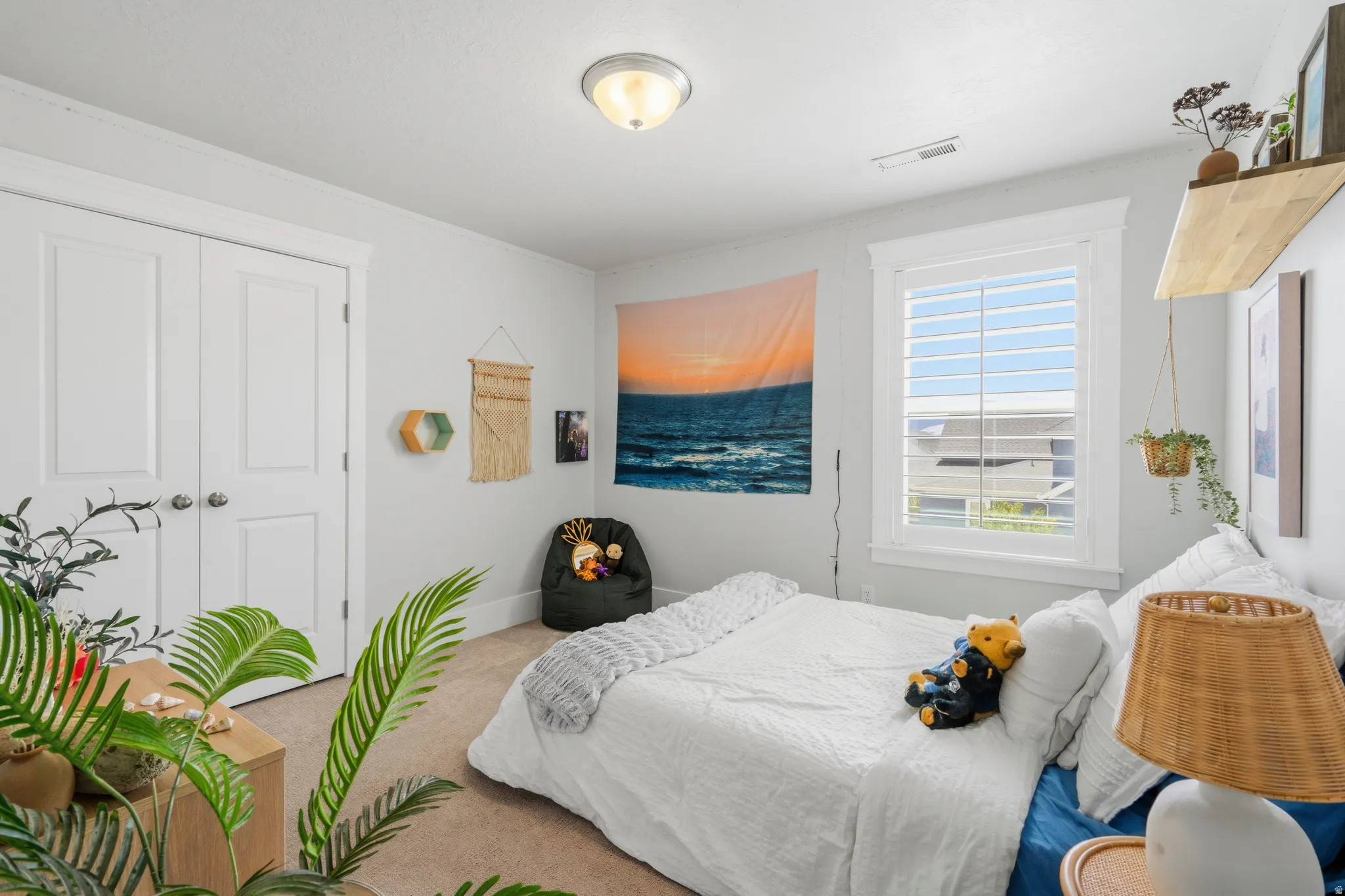 Carpeted room featuring a double-door closet with polished chrome hardware, a single window with white plantation shutters, and a flush mount ceiling light