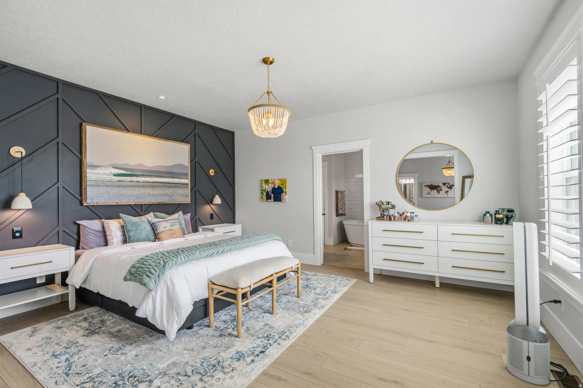 Spacious room featuring a decorative accent wall, wood-finish flooring, and a contemporary chandelier