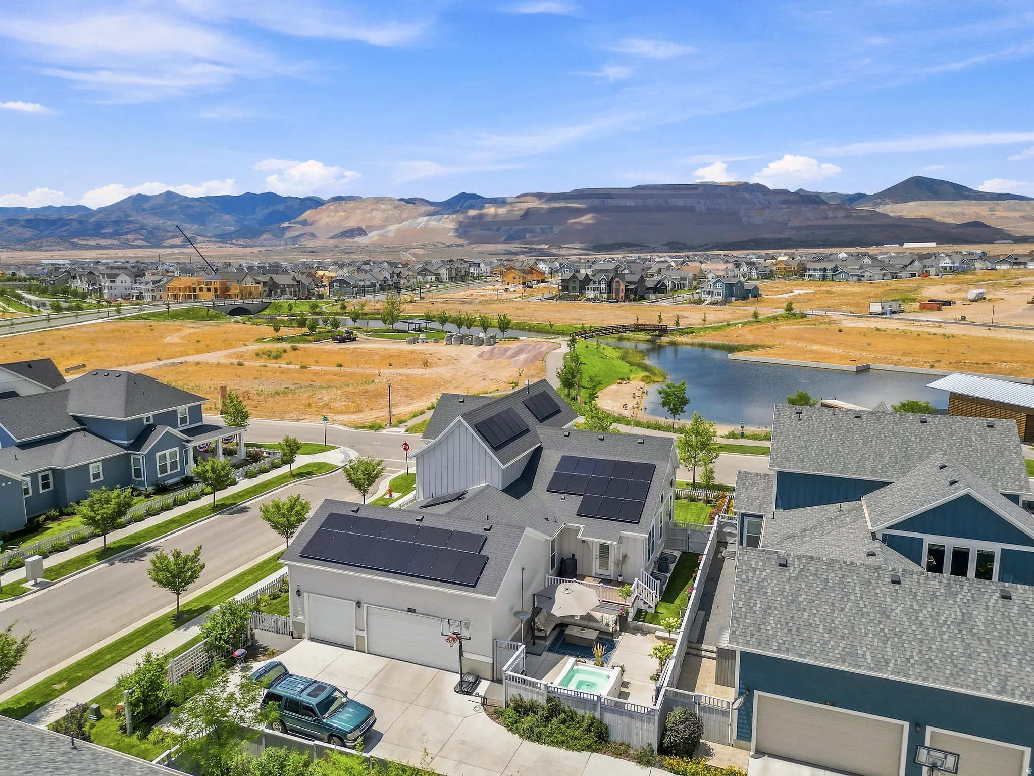 Modern residential property featuring rooftop solar panels, a two-car garage, and a private backyard patio with a built-in hot tub