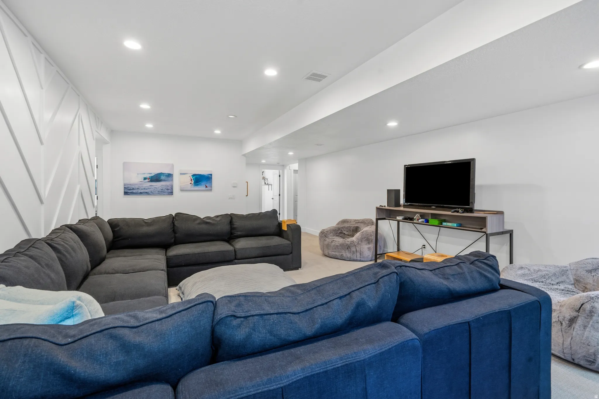 Spacious recreation room featuring recessed lighting, a decorative accent wall with diagonal paneling, and light-toned flooring