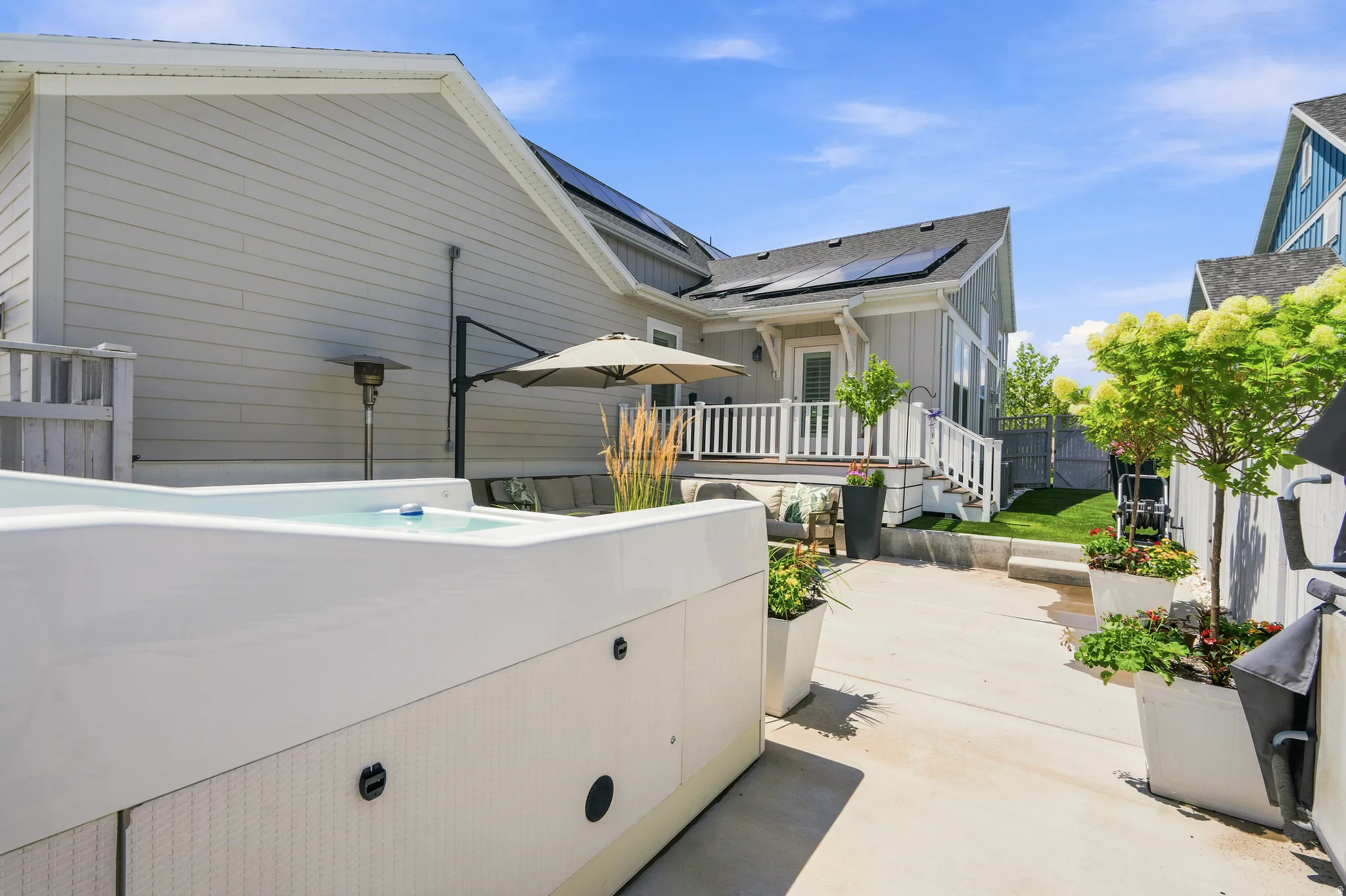 Backyard featuring a built-in spa, concrete patio, and elevated deck with white railing