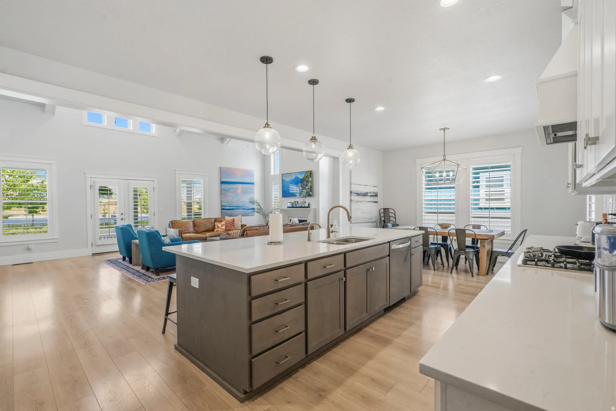 Spacious kitchen island with a built-in sink, stainless steel dishwasher, and pendant lighting