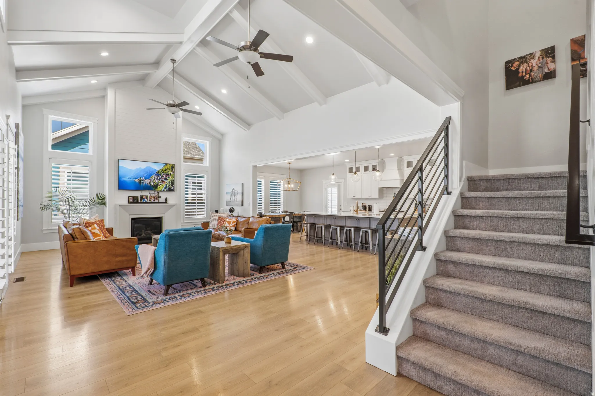Vaulted ceilings with exposed beams, light wood-finish flooring, and a fireplace with a mantel