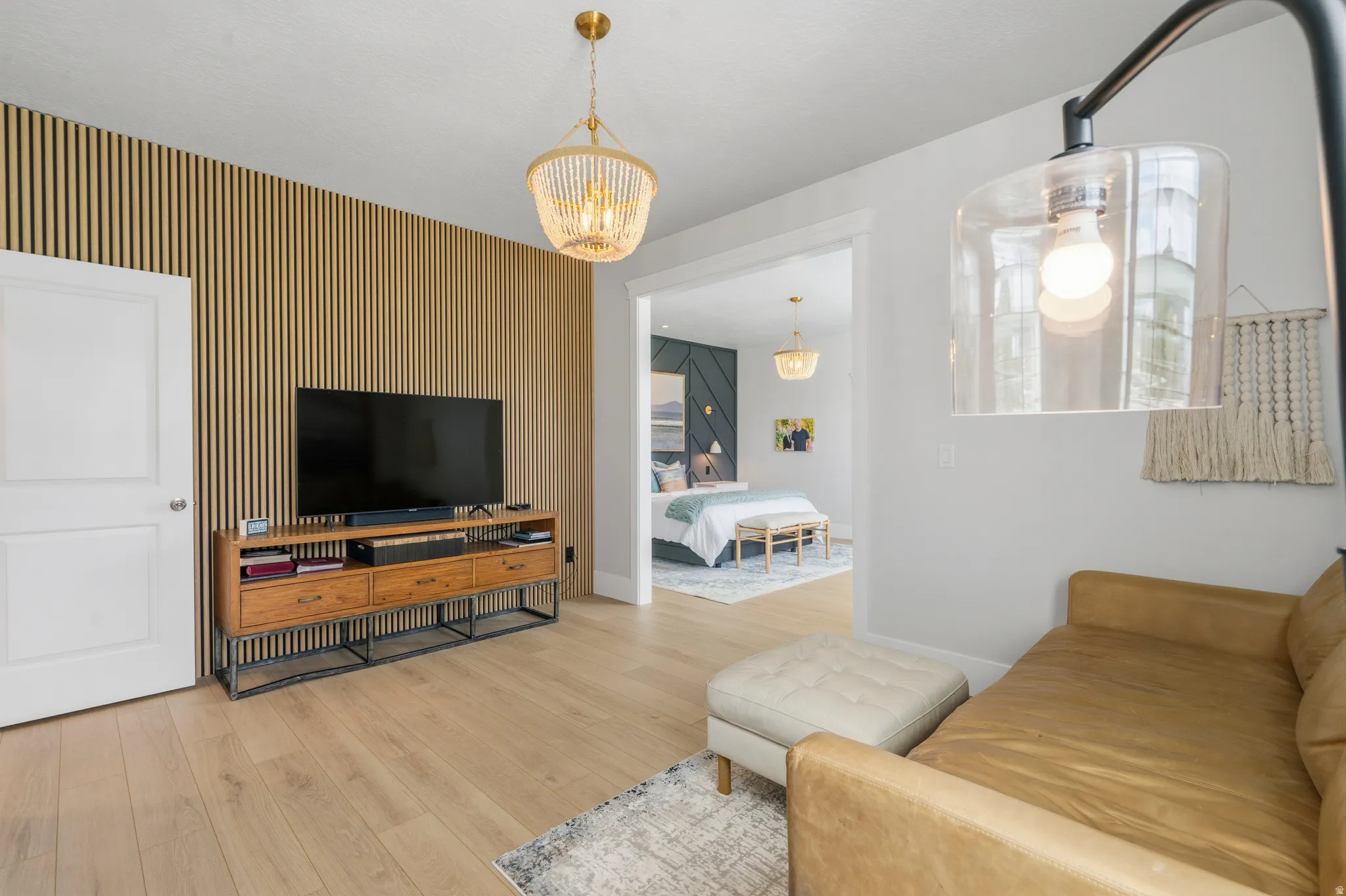 Light wood-finish flooring throughout, featuring a slatted wood accent wall and a built-in media console