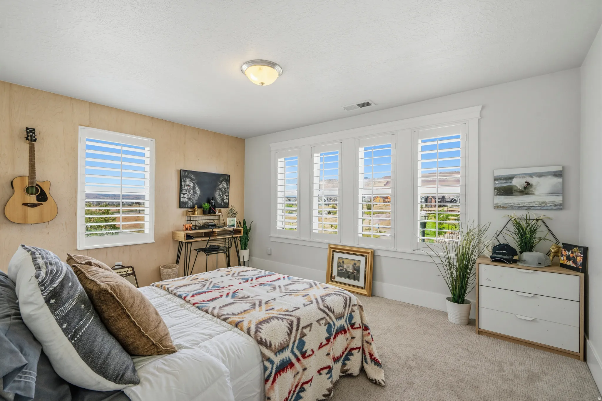 Bright interior with multiple windows featuring white plantation shutters, light gray walls, and a light-toned wood-finish accent wall
