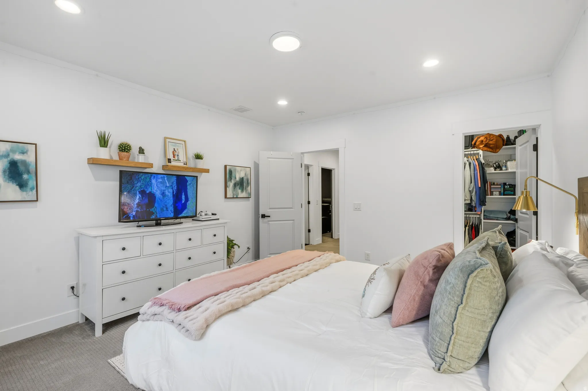 Recessed lighting illuminates the room, featuring a built-in closet with shelving and a secondary doorway