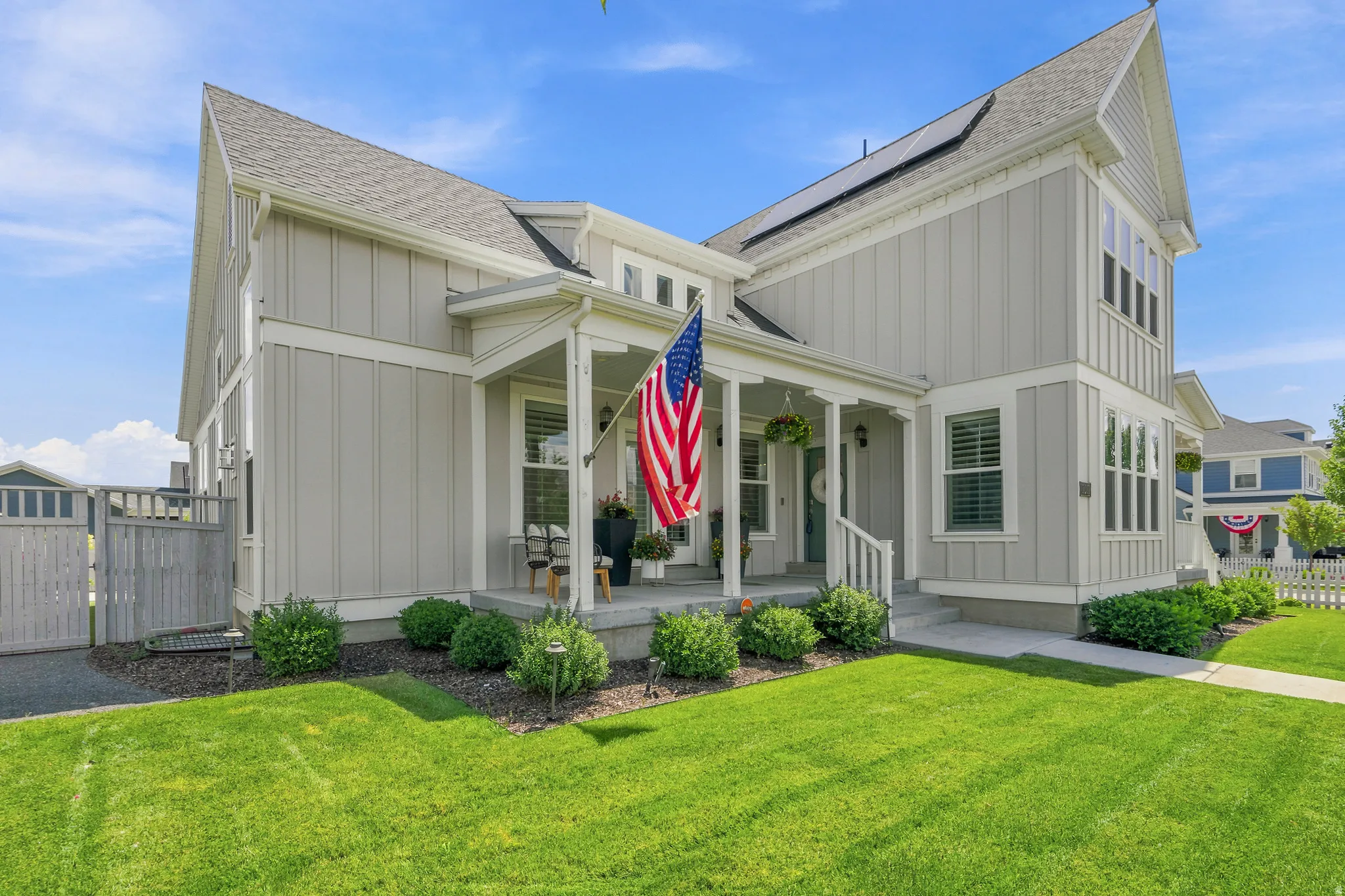 Contemporary board and batten exterior with a covered front porch, gabled roofline, solar panels, and manicured landscaping