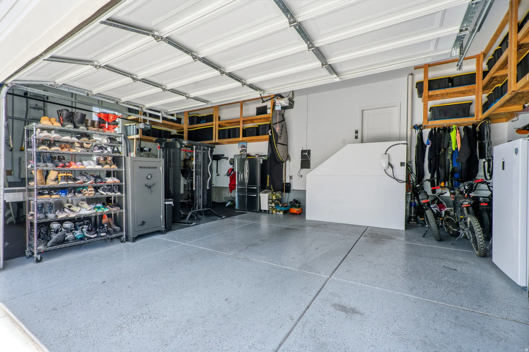 Spacious garage featuring a durable epoxy floor coating, extensive overhead wood shelving, and a prominent interior door
