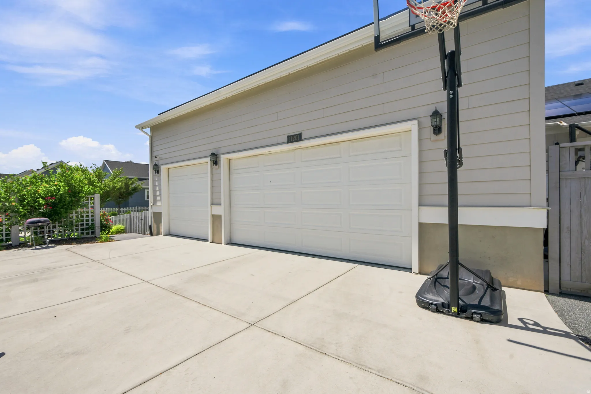 Two-car garage with white paneled doors, light gray horizontal siding, and concrete driveway