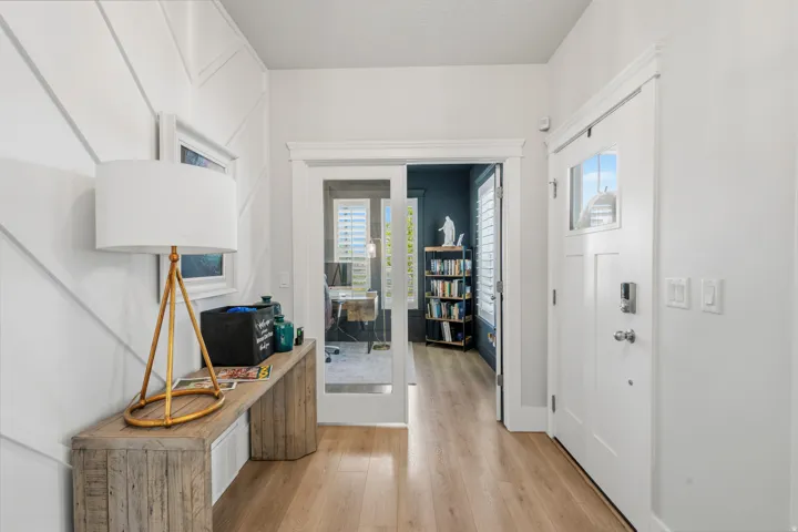 Entryway featuring chevron accent wall paneling, light wood-finish flooring, and a solid core entry door with frosted glass detailing