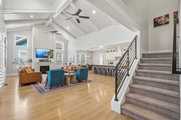 Vaulted ceilings with exposed beams, light wood-finish flooring, and a fireplace with a mantel
