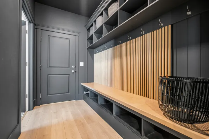 Mudroom with wood-finish flooring, built-in bench seating, storage cubbies, wall hooks, and upper shelving units