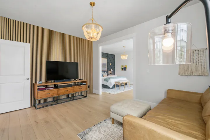 Light wood-finish flooring throughout, featuring a slatted wood accent wall and a built-in media console