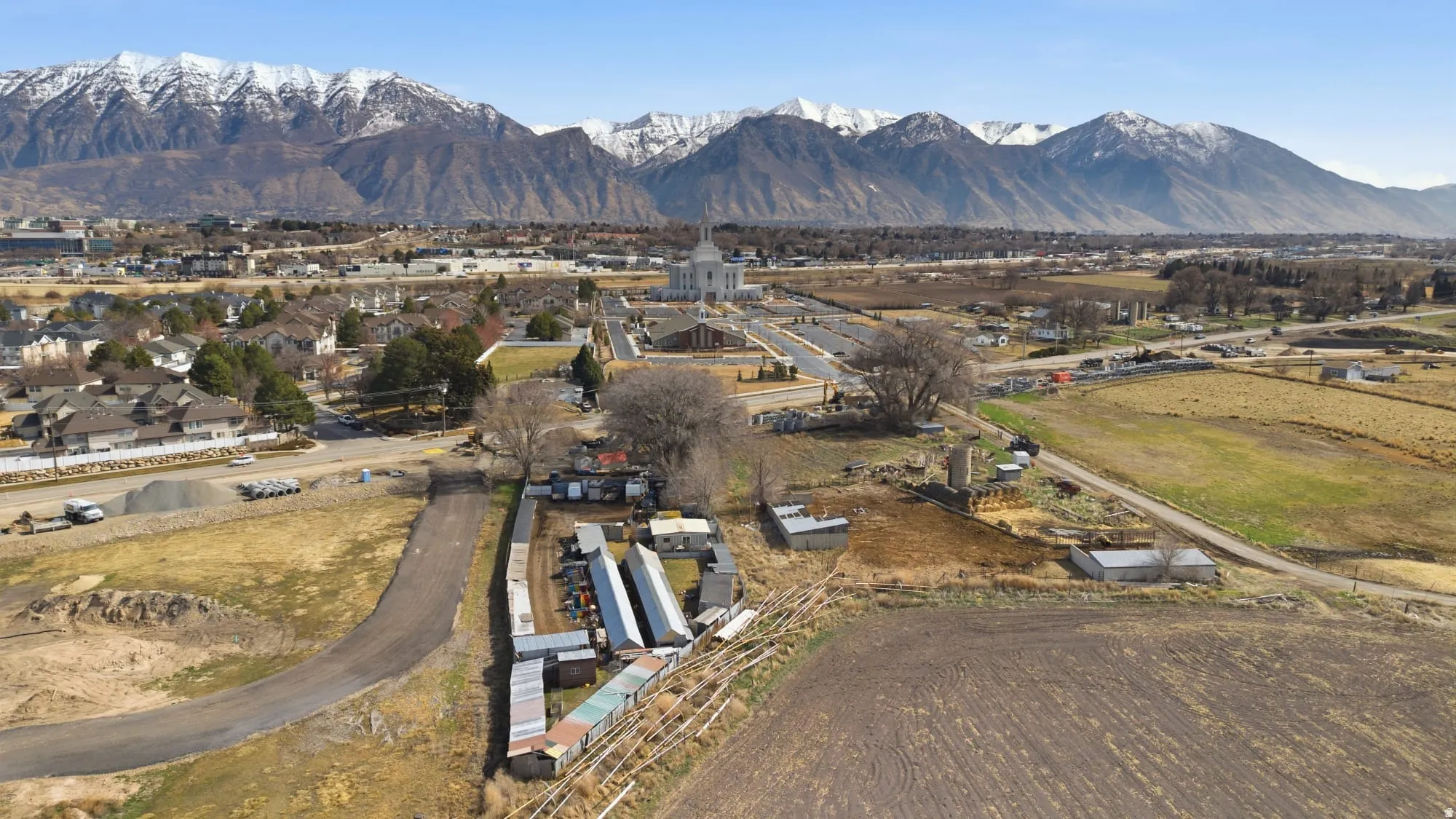 Expansive land parcel featuring a gravel access road and multiple outbuildings