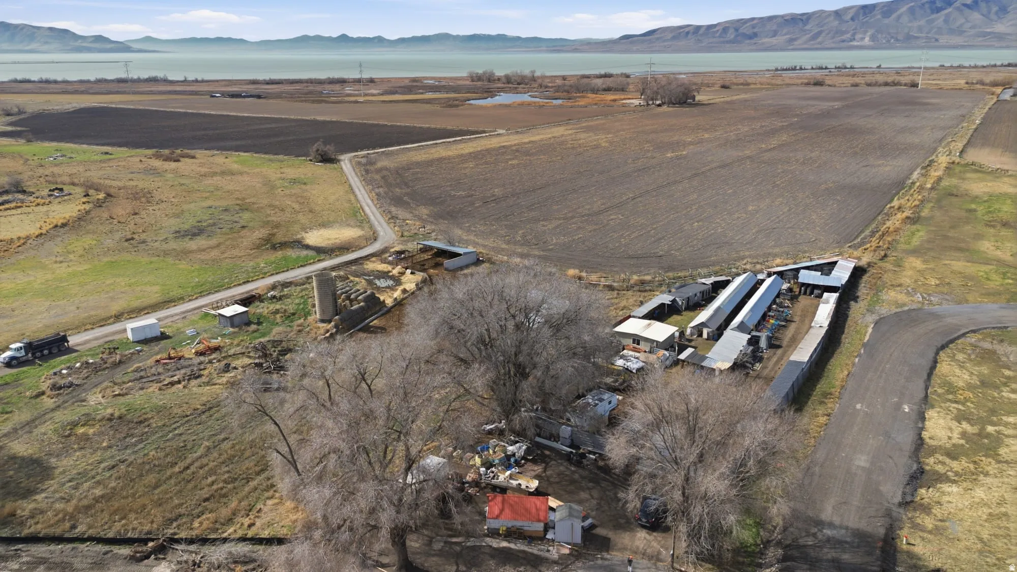 Expansive agricultural land featuring multiple outbuildings, including long structures with metal roofs and a silo