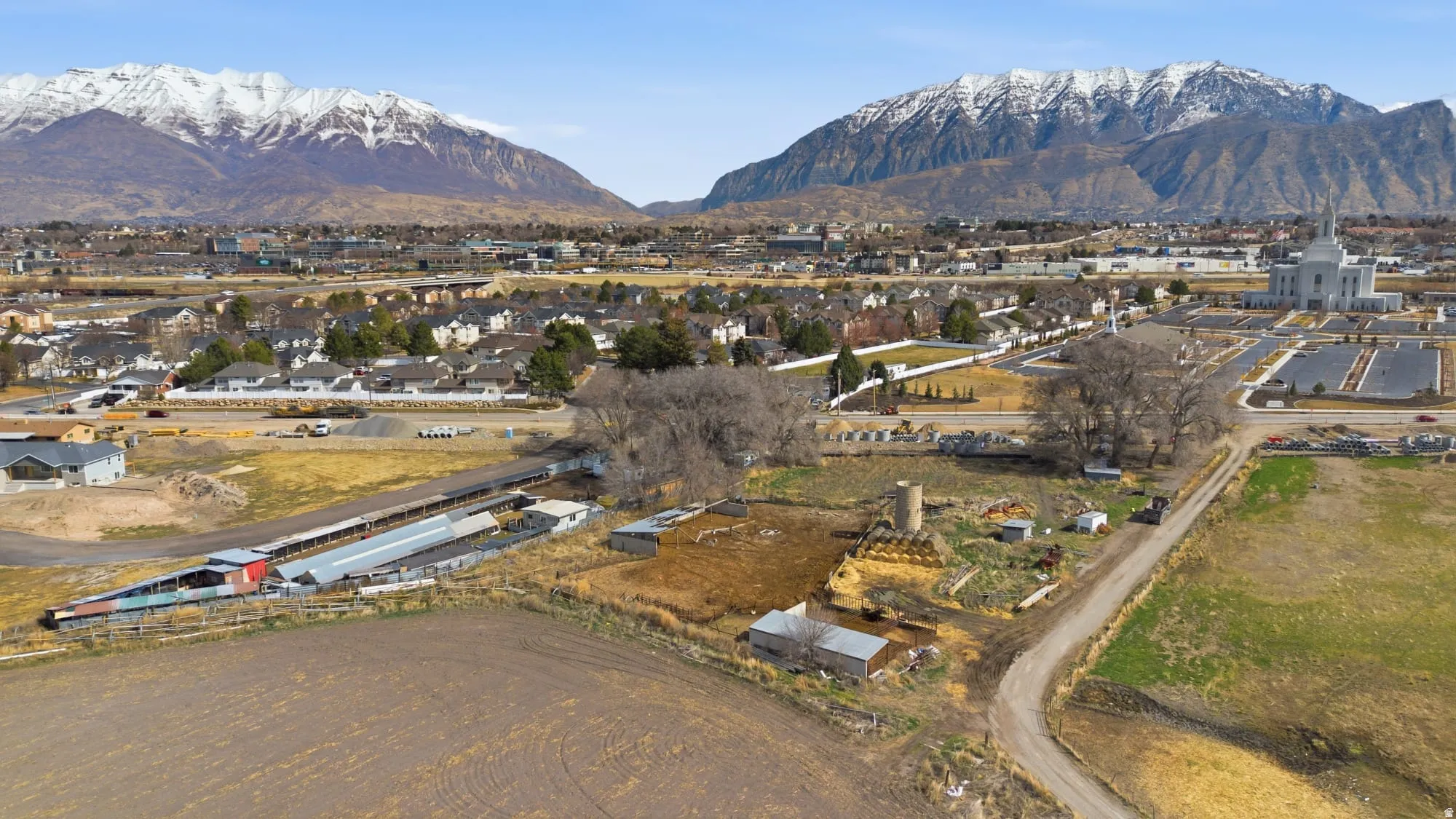 Expansive land parcel featuring open fields, existing outbuildings, and a dirt road