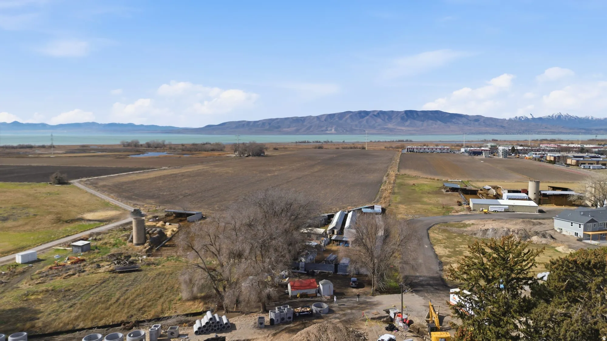 Expansive land parcel featuring a paved road, mature trees, and a distant body of water