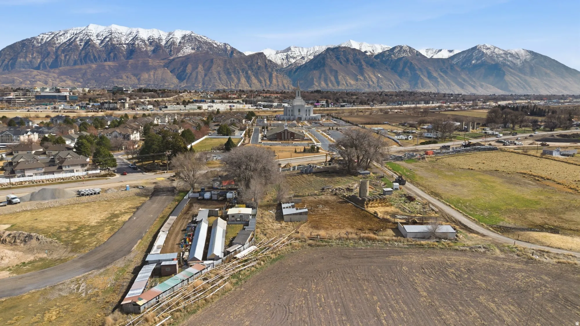 Expansive land parcel featuring a central paved driveway, surrounding cultivated fields, and multiple outbuildings
