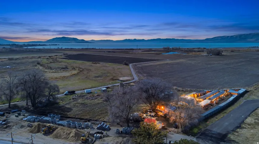 Expansive rural property featuring multiple structures, cultivated land, and a body of water in the background