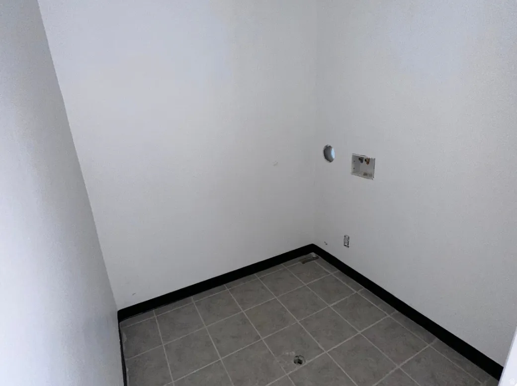 Utility space featuring light gray ceramic tile flooring and white textured walls