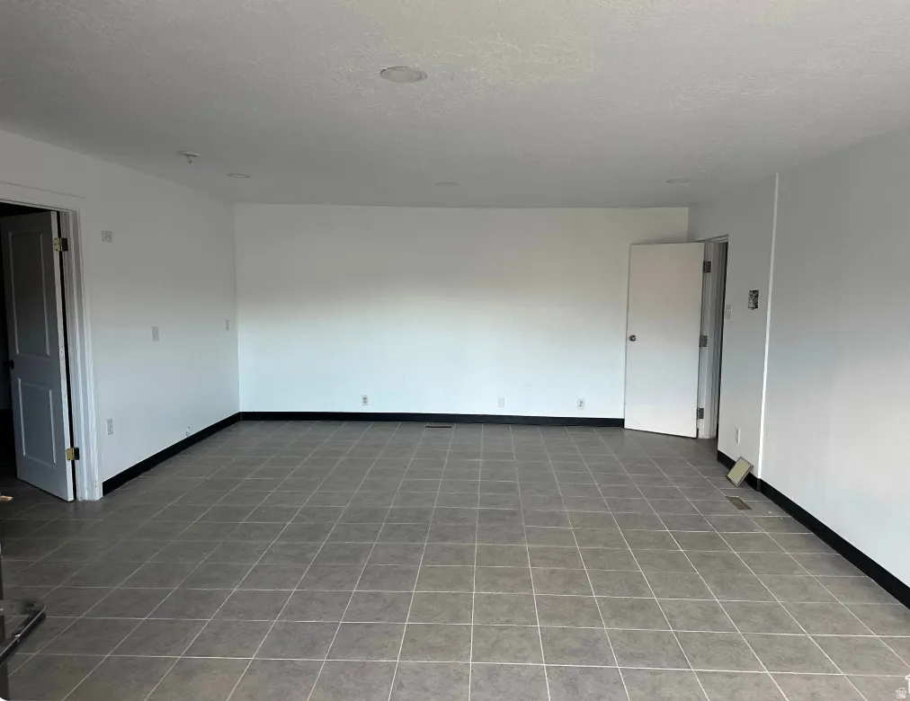 Spacious room featuring neutral white walls and grey tiled flooring