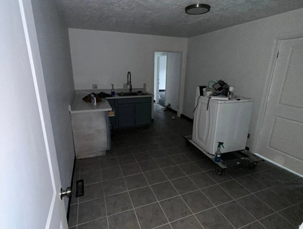 Utility area featuring tiled flooring, a built-in countertop with a sink, cabinetry, and a ceiling-mounted light fixture