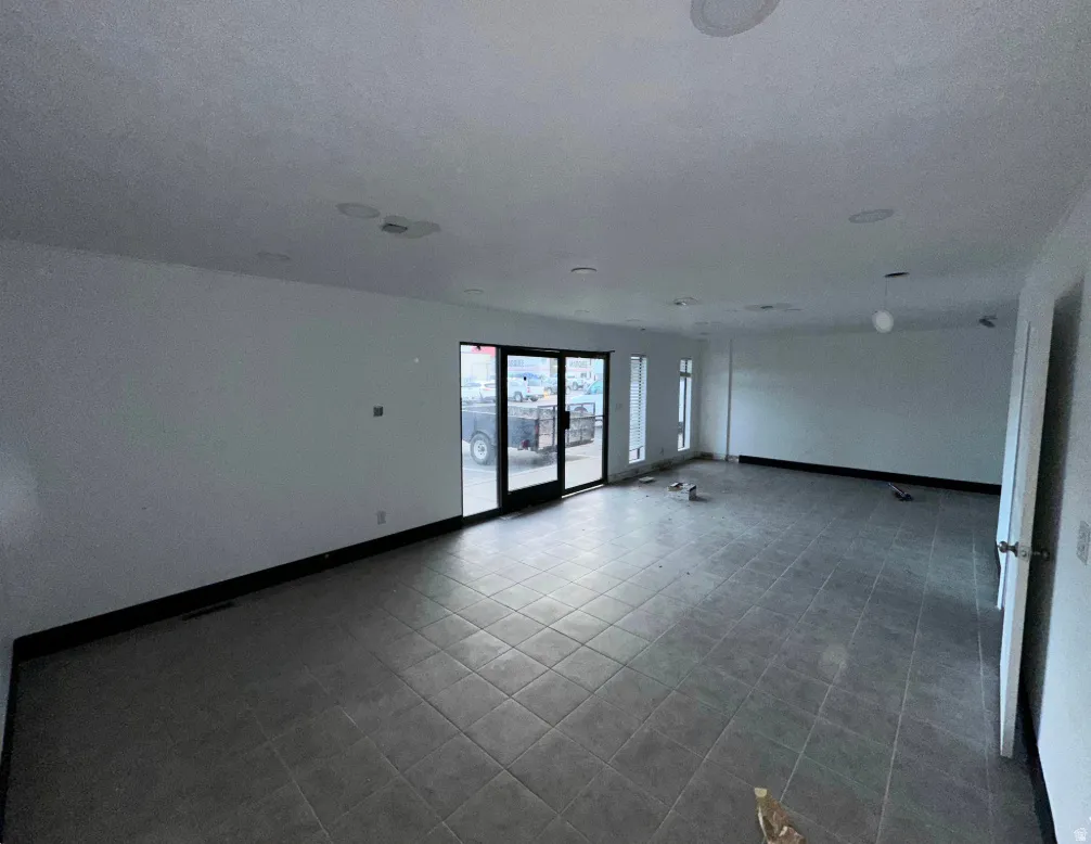 Spacious room featuring neutral-toned tile flooring and white walls
