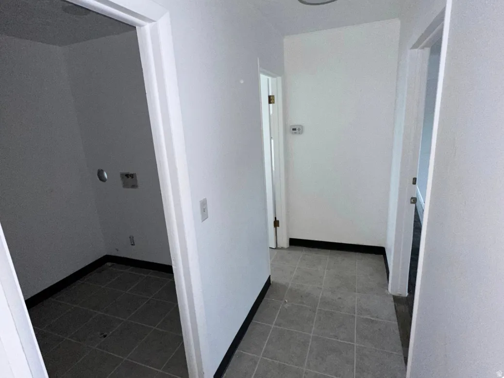 Tiled utility area with white walls and a dark baseboard trim