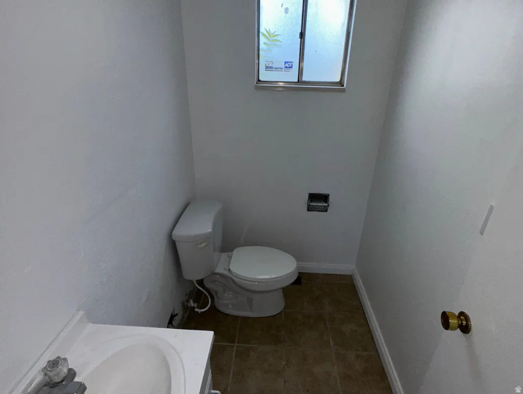 Bathroom featuring a white toilet, a frosted window, and a vanity with an integrated sink