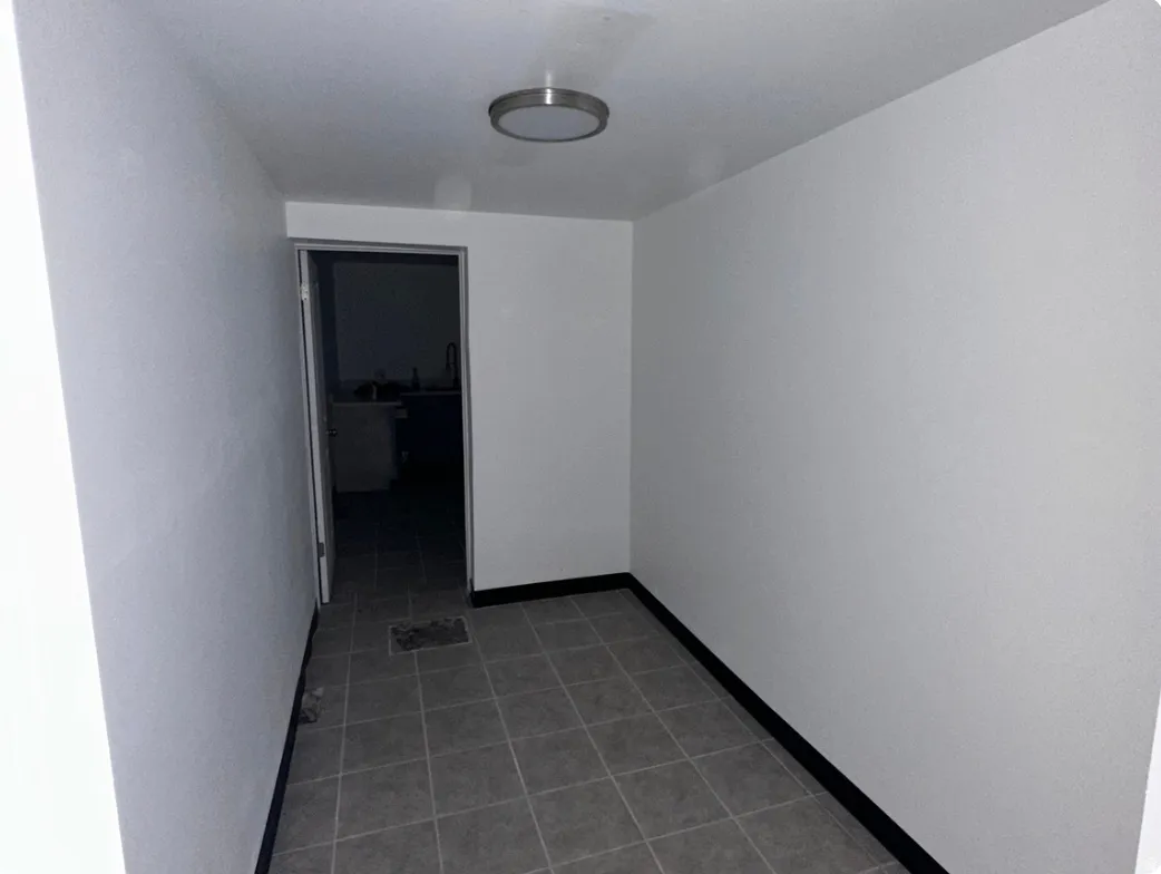 Interior space featuring light gray walls, dark baseboards, and gray tile flooring