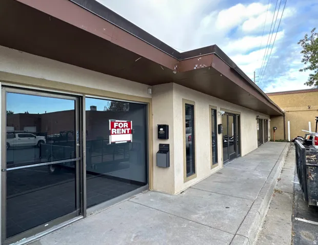 Commercial storefront featuring a stucco facade, multiple large windows, and a wide concrete walkway