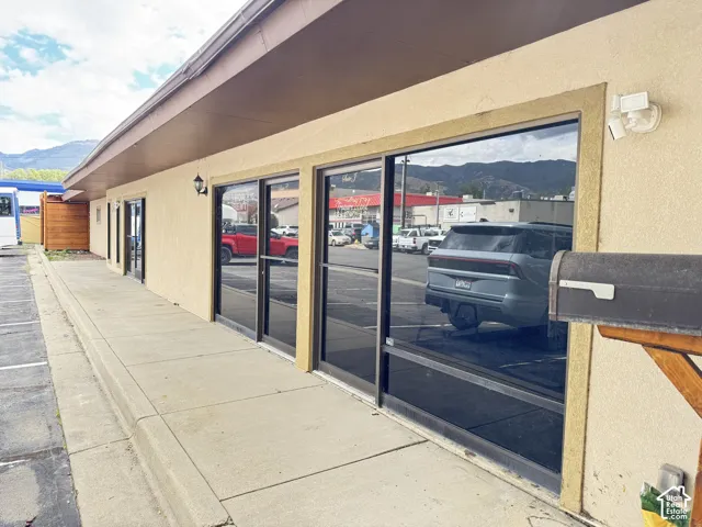 Stucco exterior with multiple storefront windows, a concrete walkway, and an attached awning
