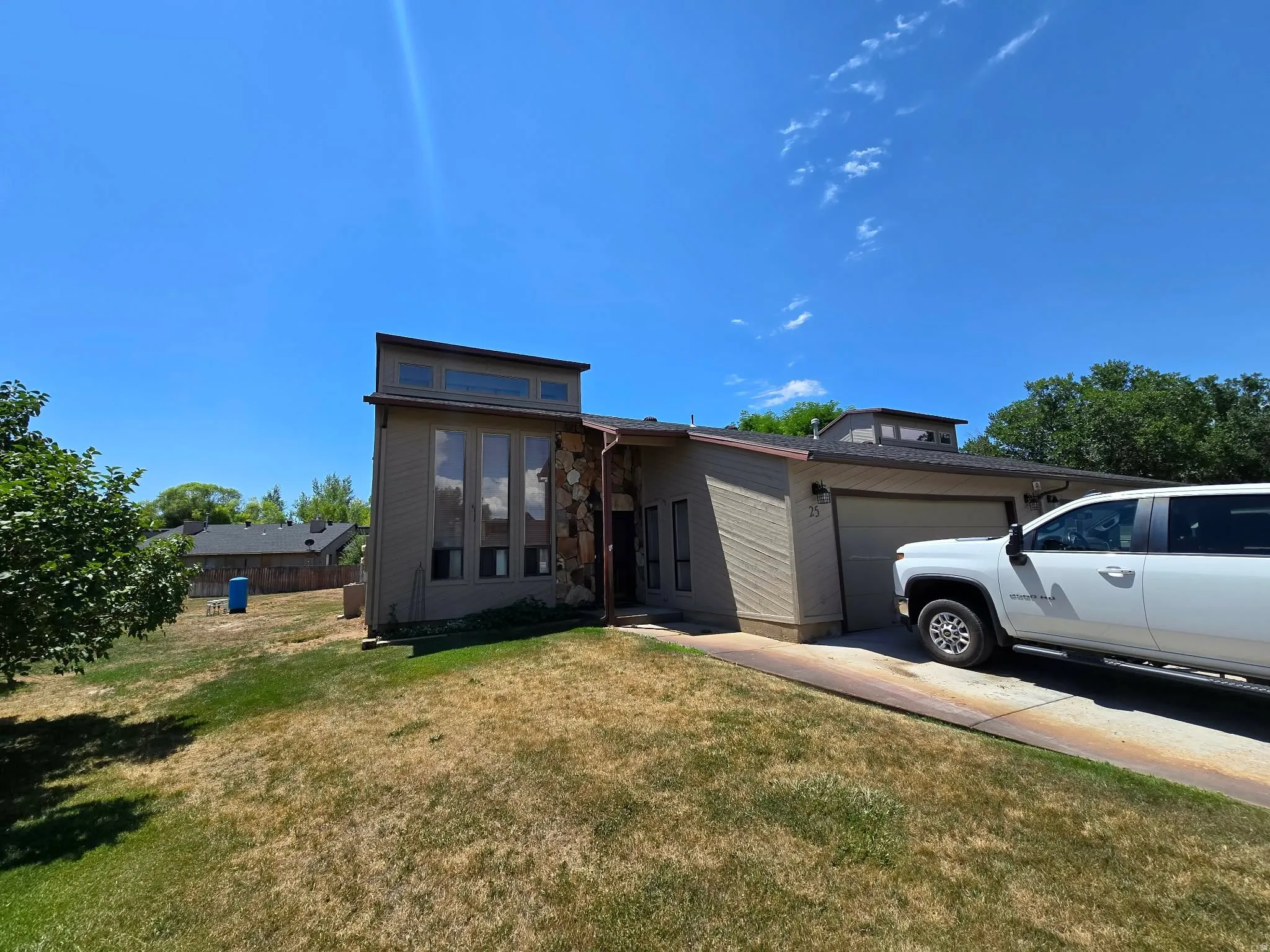 Contemporary exterior featuring stacked stone accents, vertical window array, and a two-car garage
