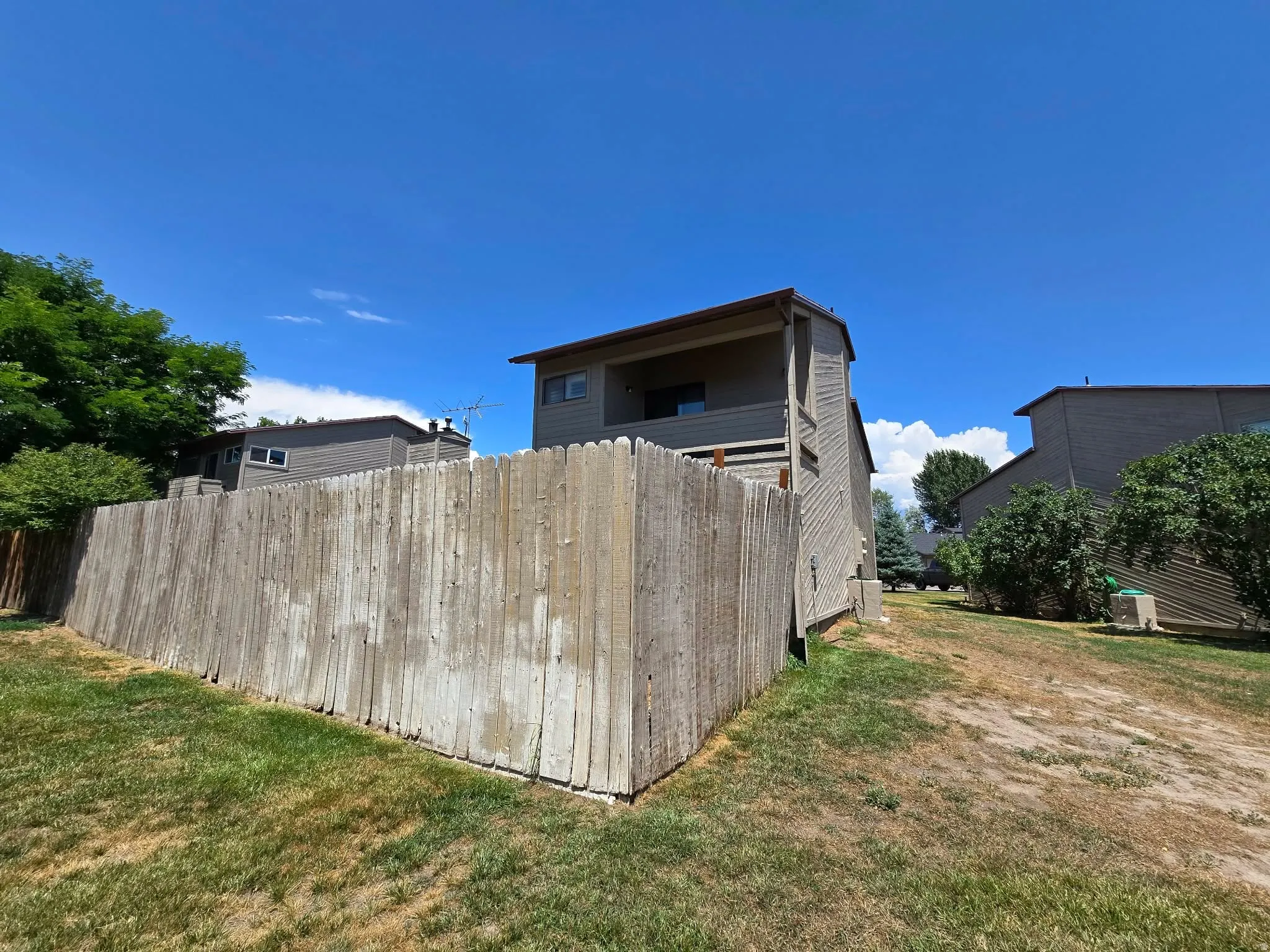 Wood privacy fence bordering a grass area with mature trees