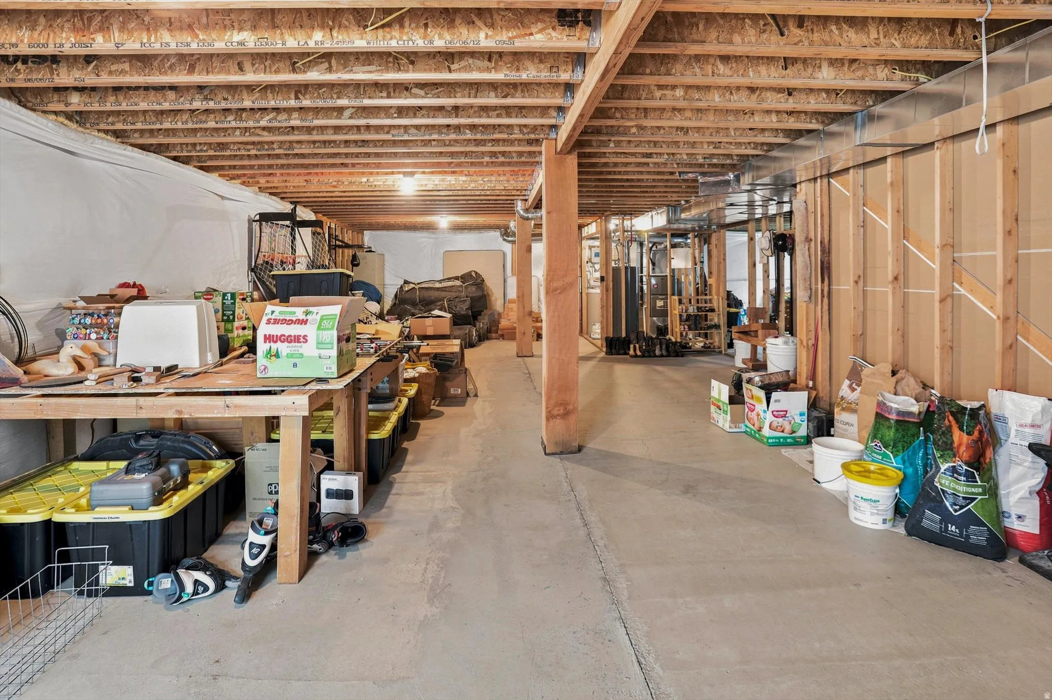 Unfinished basement offering substantial square footage, exposed wooden ceiling joists, concrete flooring, and framed walls