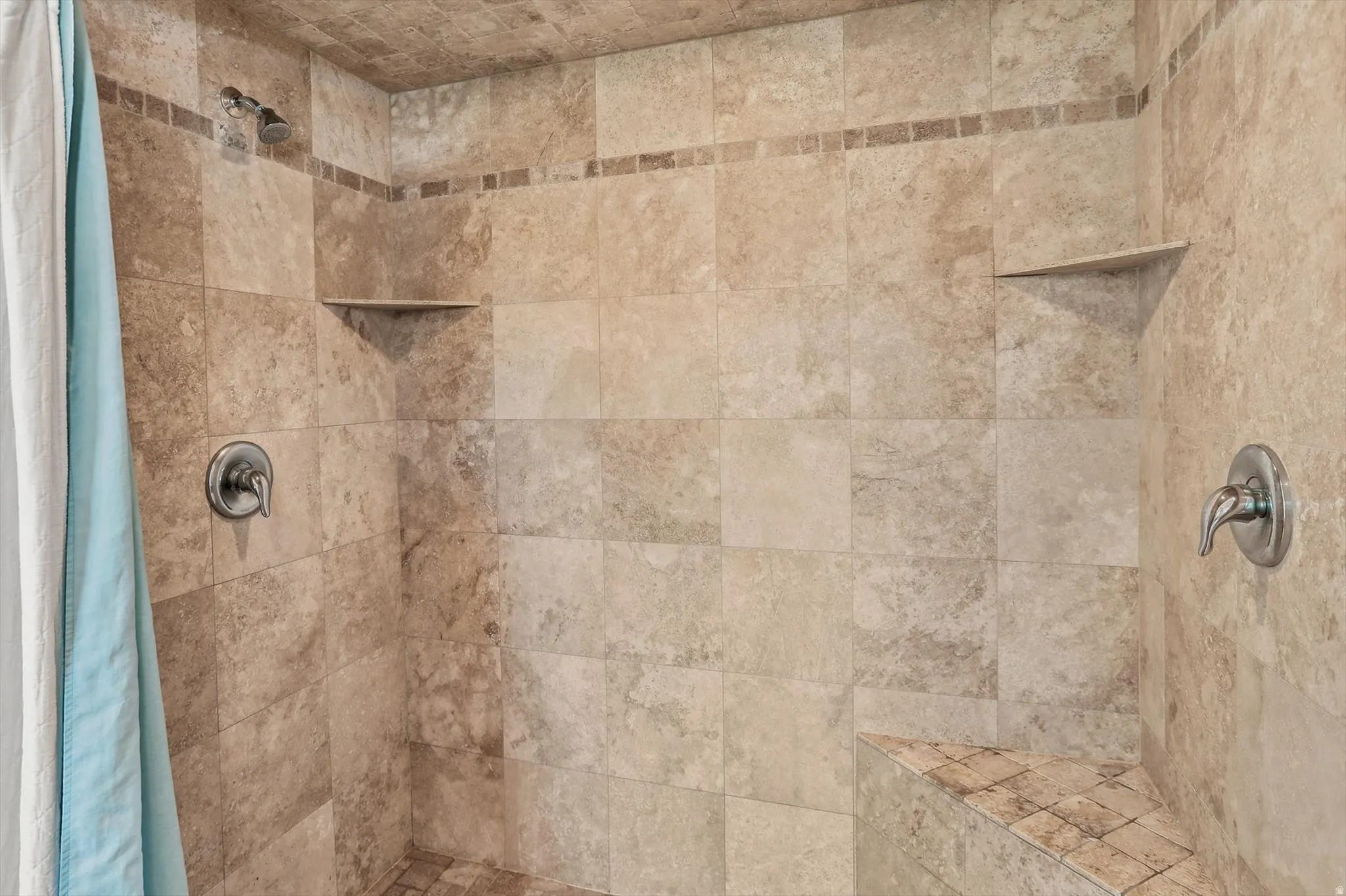 Tiled shower featuring dual shower heads, integrated corner shelving, a tiled bench, and brushed nickel fixtures