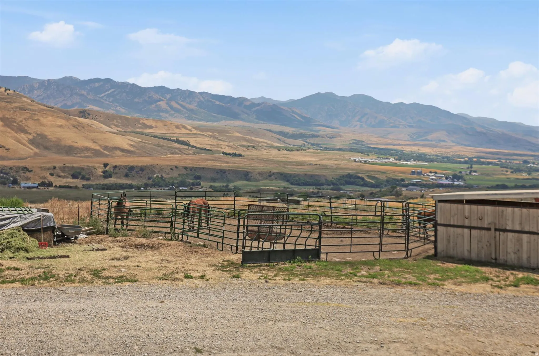 Expansive property featuring a metal fenced corral, a wood-sided outbuilding, and gravel ground cover